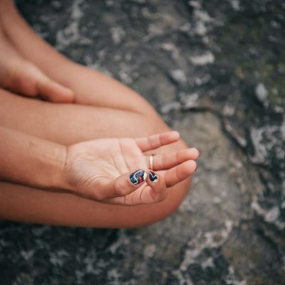 Close up of hands in a mudra position against black.